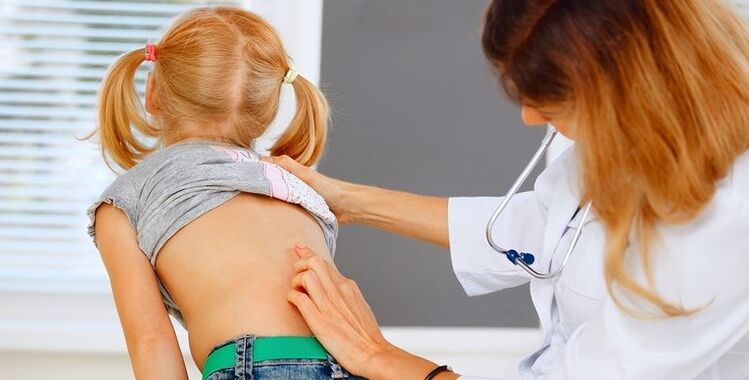 doctor examining the back of a child with lower back pain